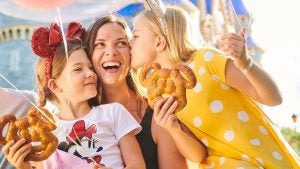 a mother with two daughters holding mickey mouse-shaped pretzels