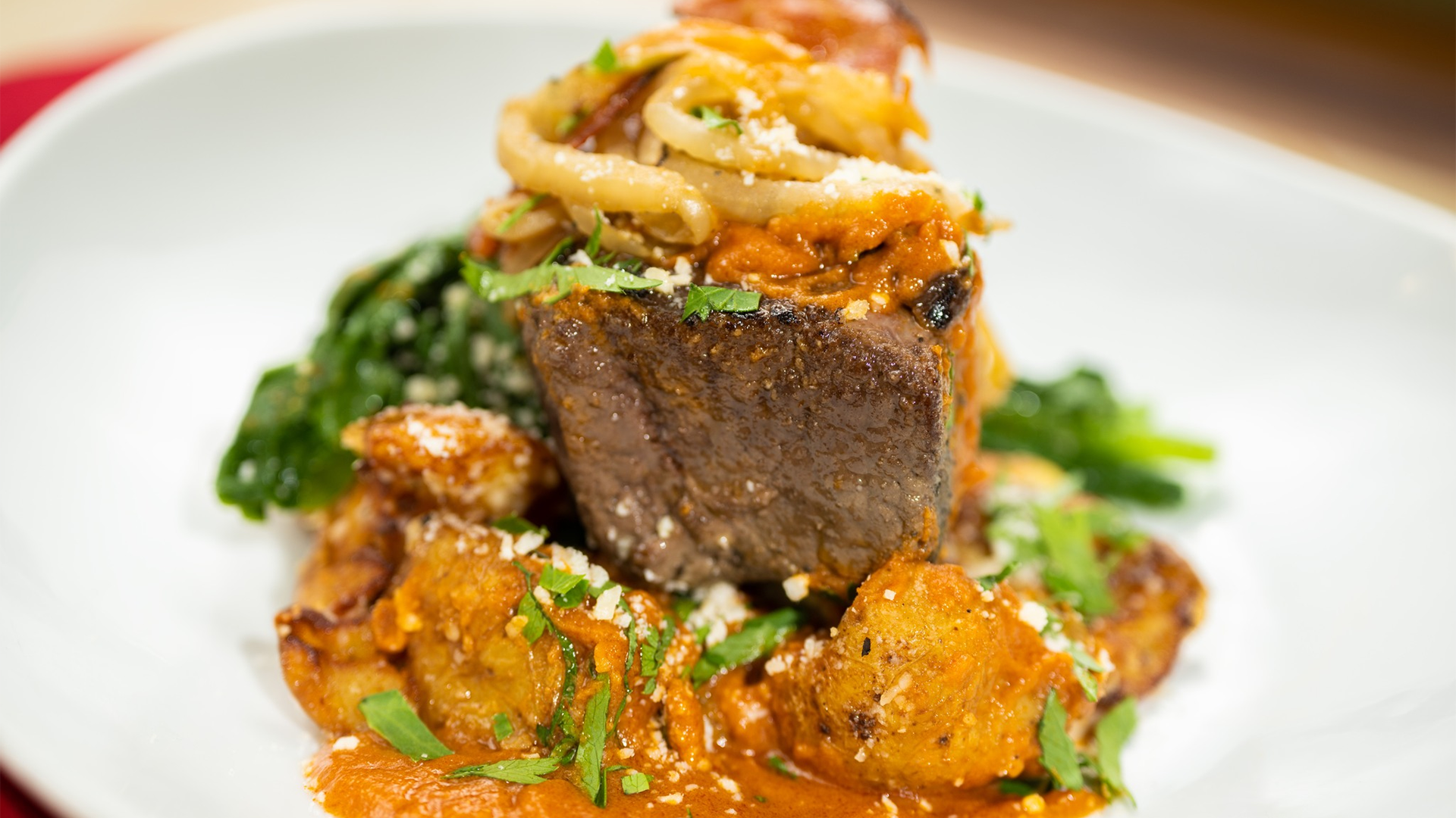 s steak dish with pasta, red sauce, and herbs on the side