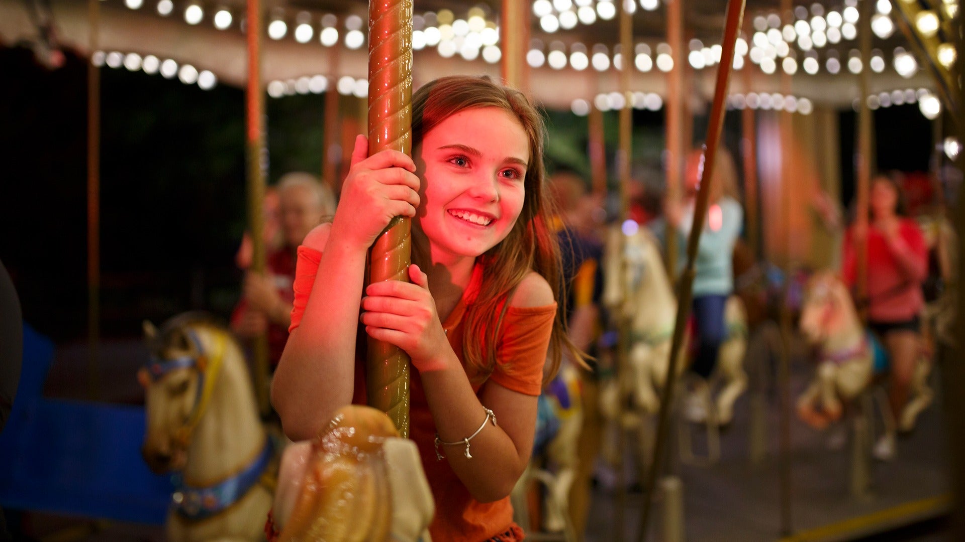 a young girl riding a carousel in dollywood at night
