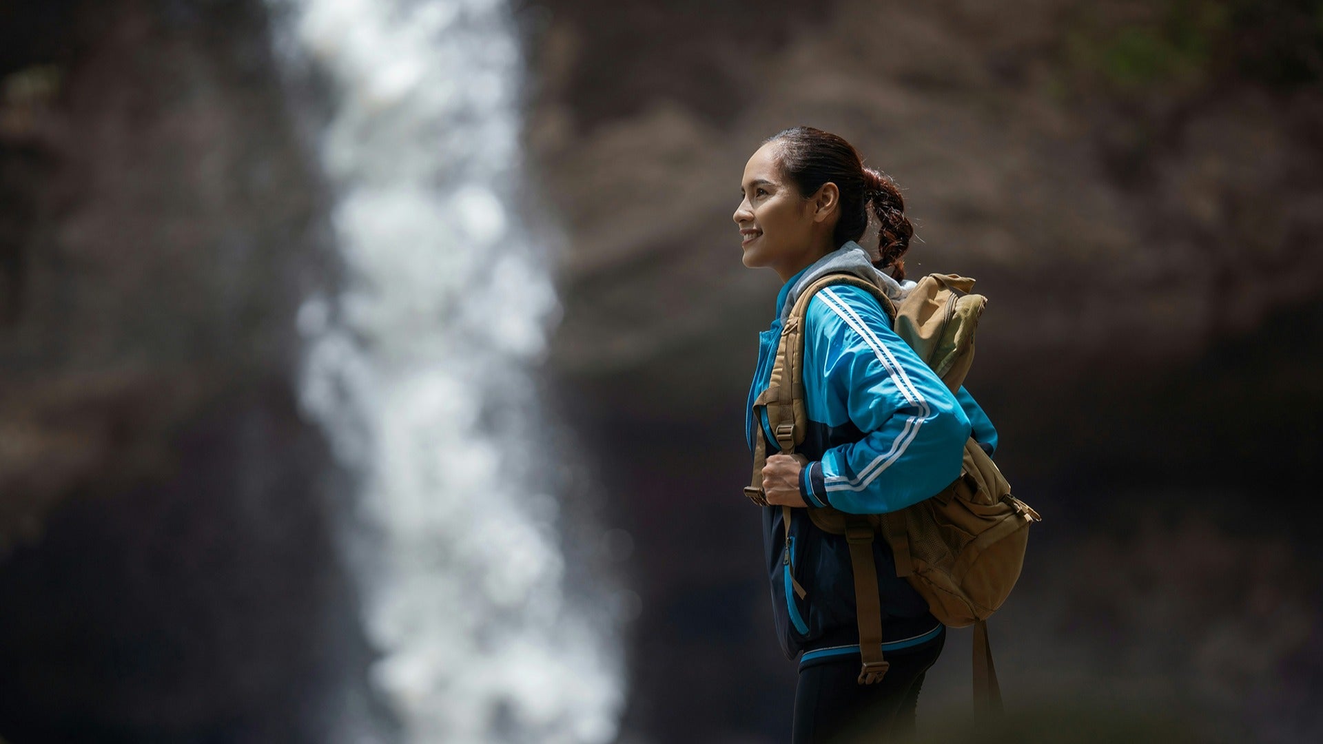 a hiker wearing gear and a backpack with a view of waterfalls at the back