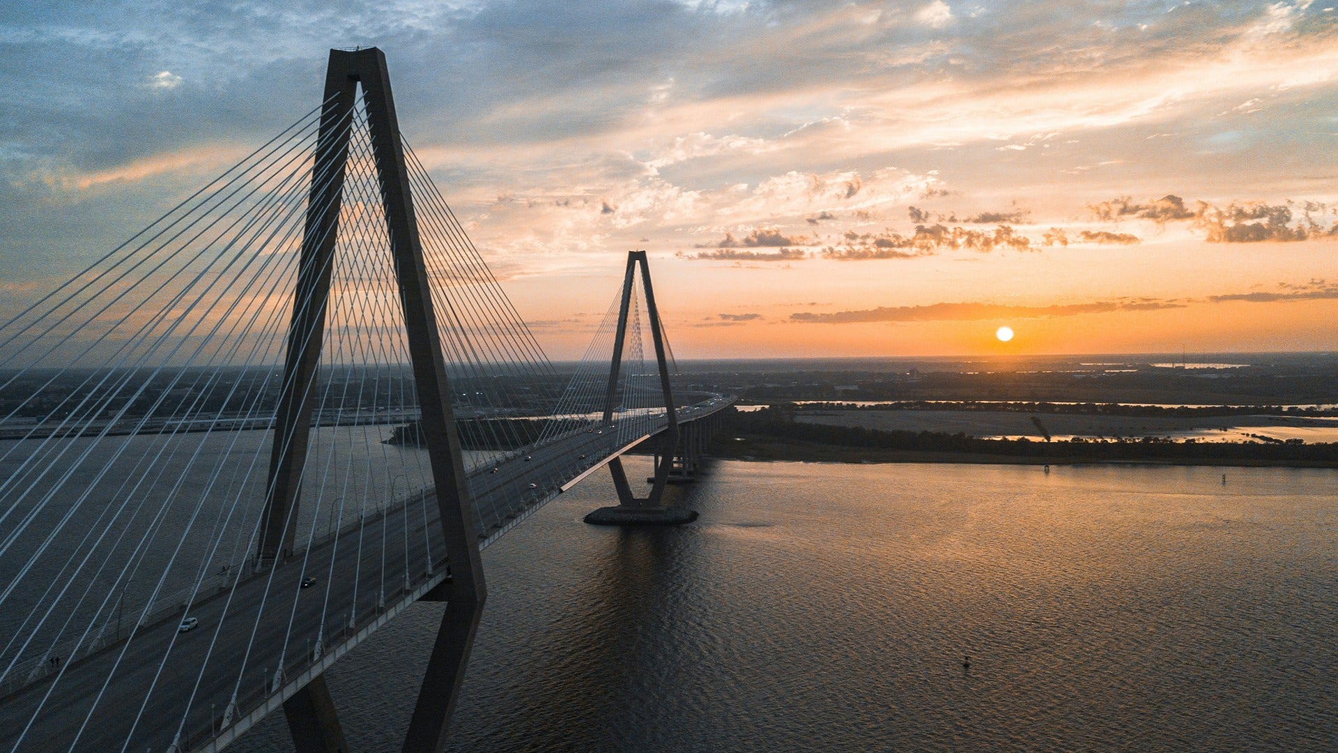 a bridge with views of the ocean and a sunset over the city skyline