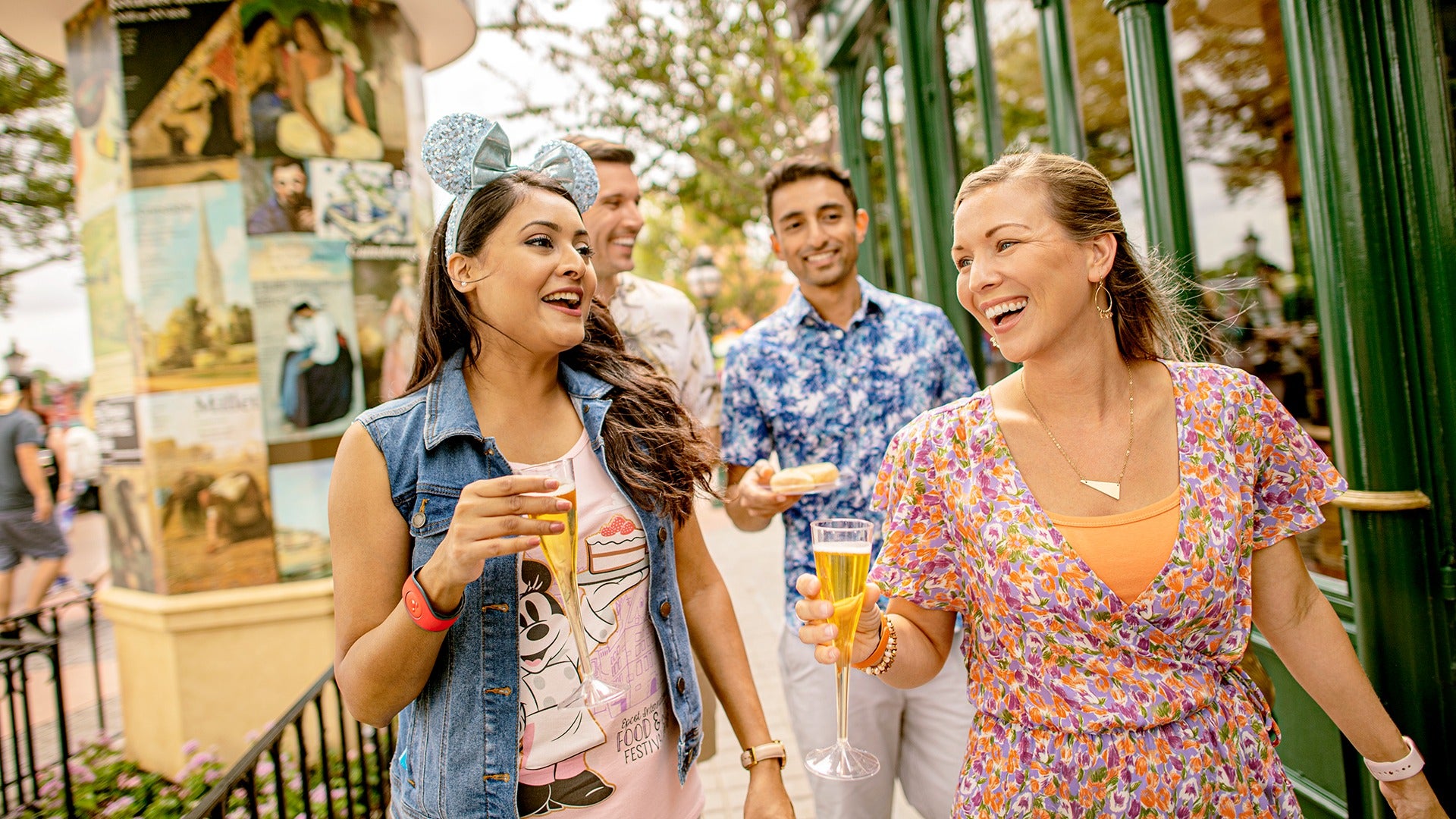 a group of friends drinking wine and eating food while wearing mickey ears, walking around disney world