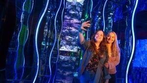 two women snapping pics in front of an aquarium feature