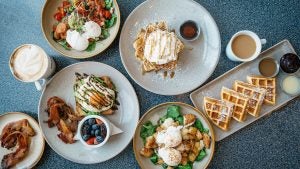 an assortment of breakfast food with pancakes and waffles and salads and more