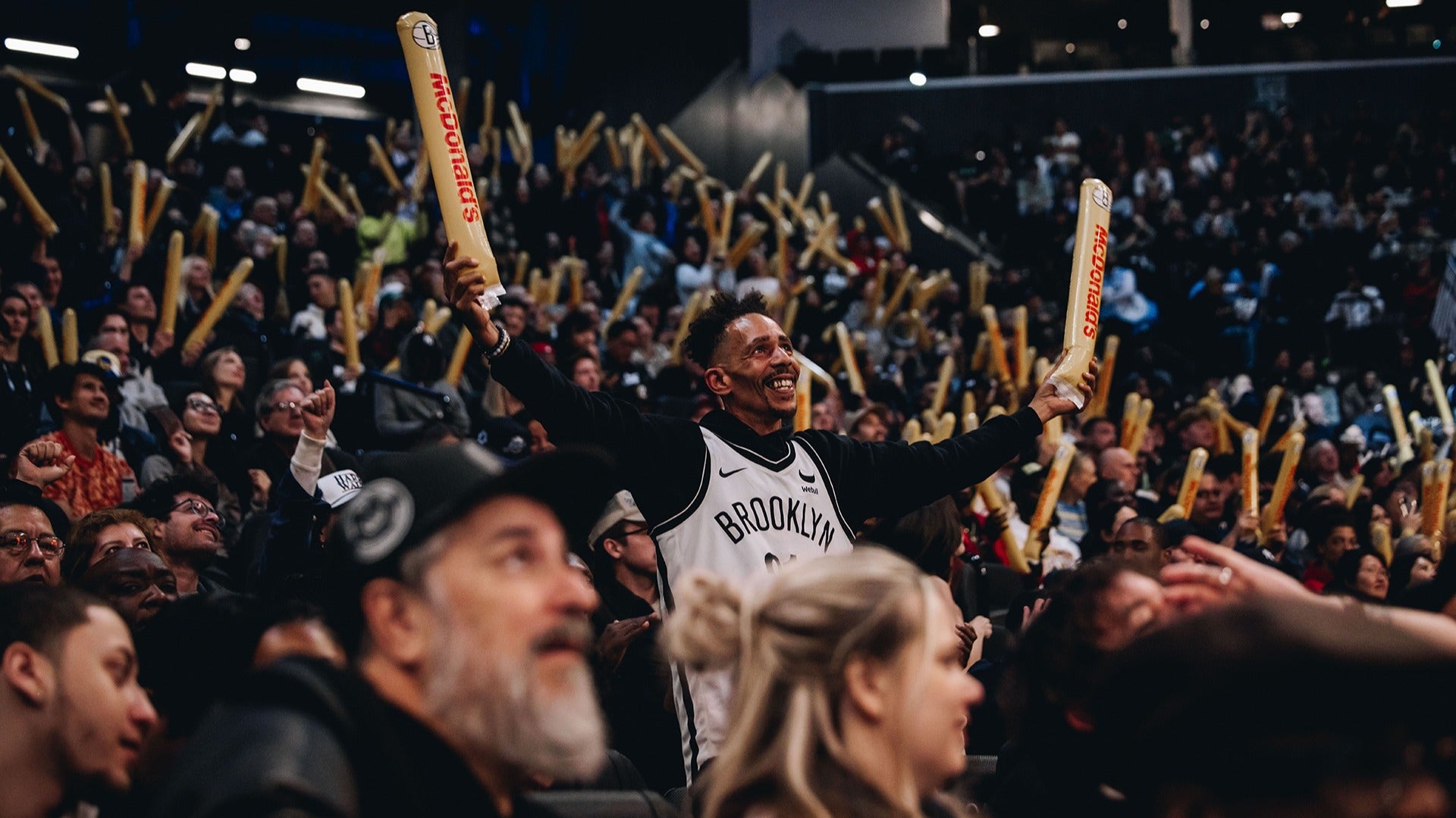 fans in the audience of basketball game cheering and raising clappers