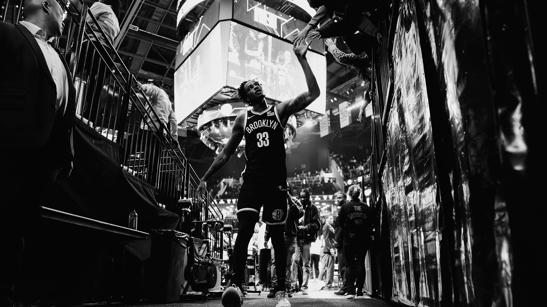 a basketball player walking to the locker rooms high fiving with fans