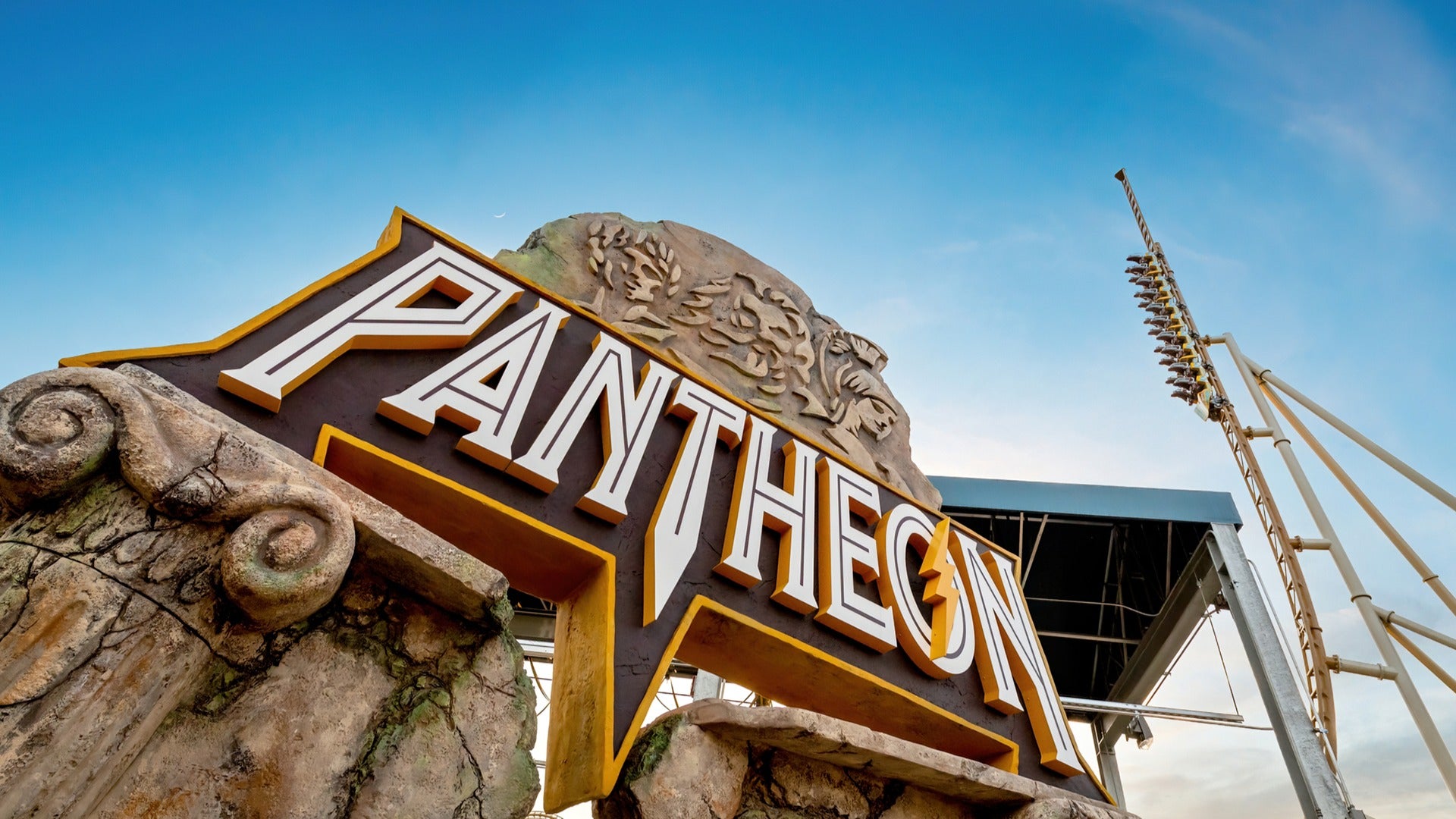 a signage for an amusement park ride with the roller coaster at the back