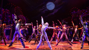 people in cats costumes performing on a stage with a full on production design set
