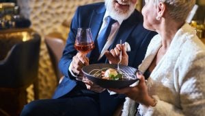a couple on a romantic dinner holding wine and a plate of food