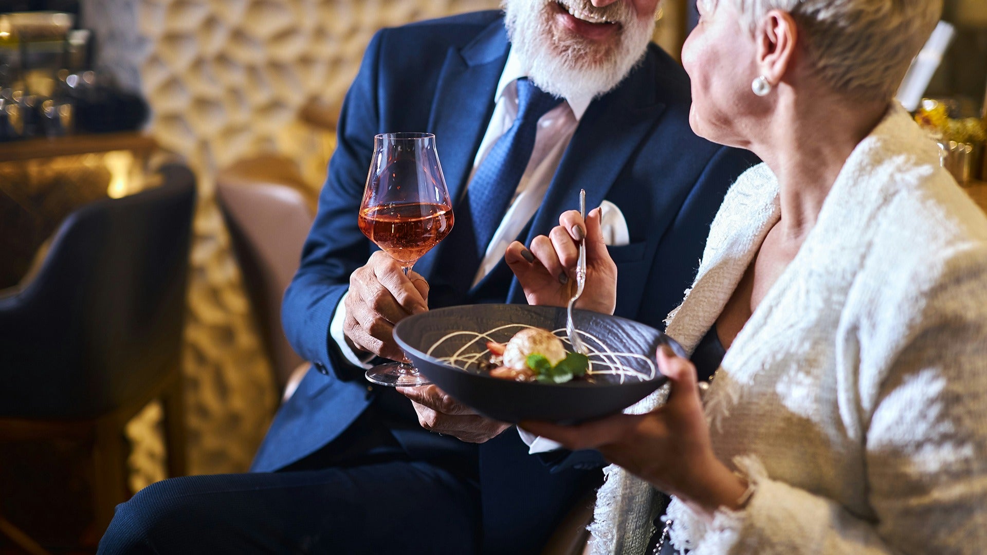 a couple on a romantic dinner holding wine and a plate of food