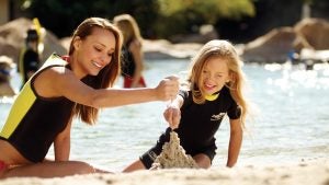 woman and child playing on a seashore with sand