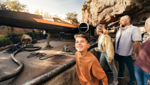 a family walking through the star wars galaxy in disneyland with a spaceship at the back