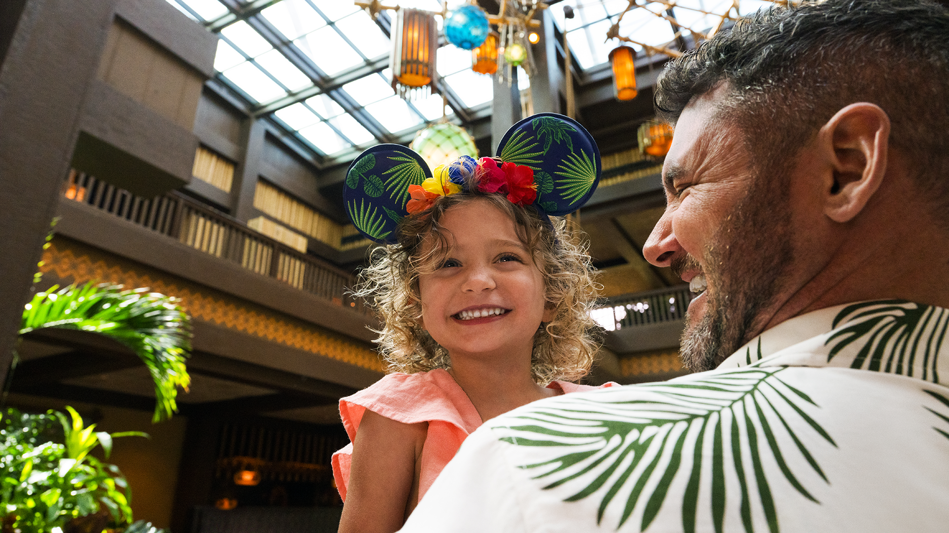 father holding his daughter who's wearing mickey ears