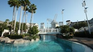 a pool in a resort with a bridge and a windmill and trees