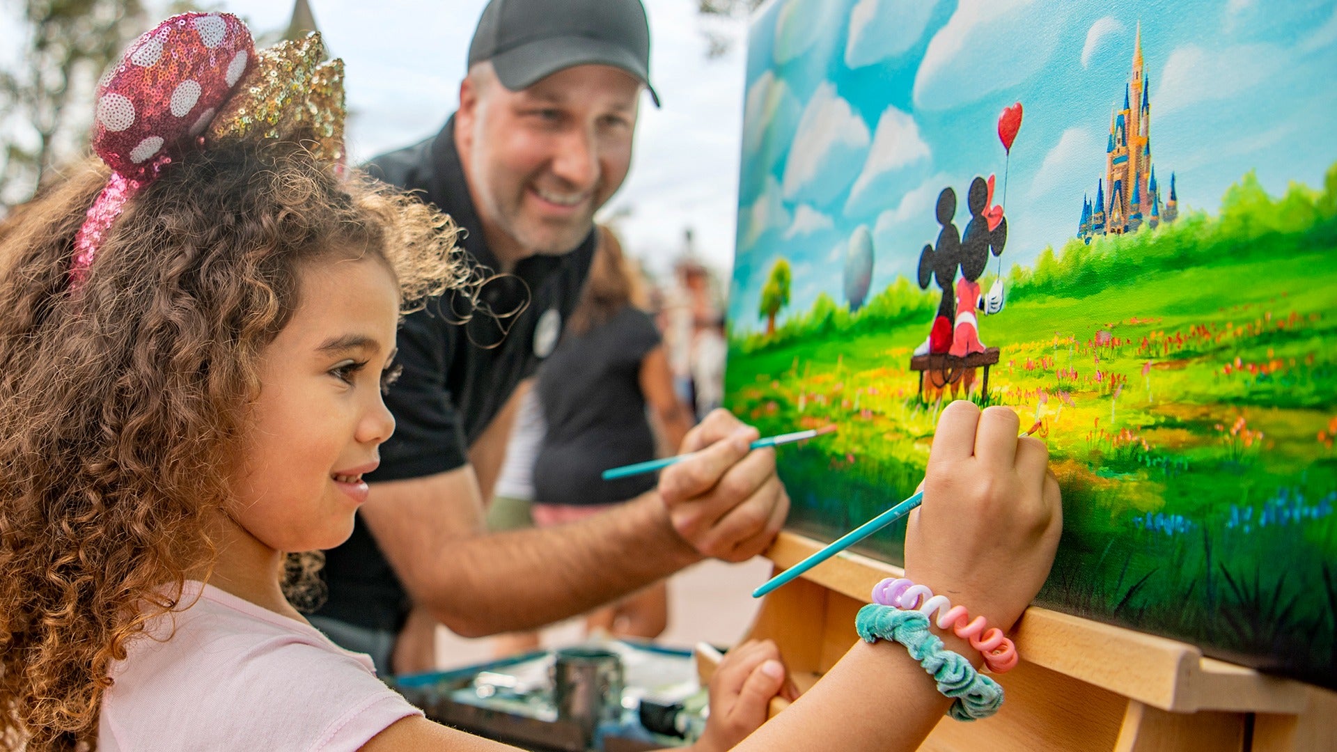 a man helping a child paint, both having fun