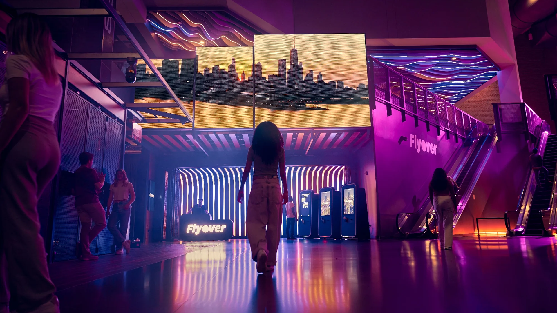 a woman in a neon lit entrance staring at a led wall of chicago skyline