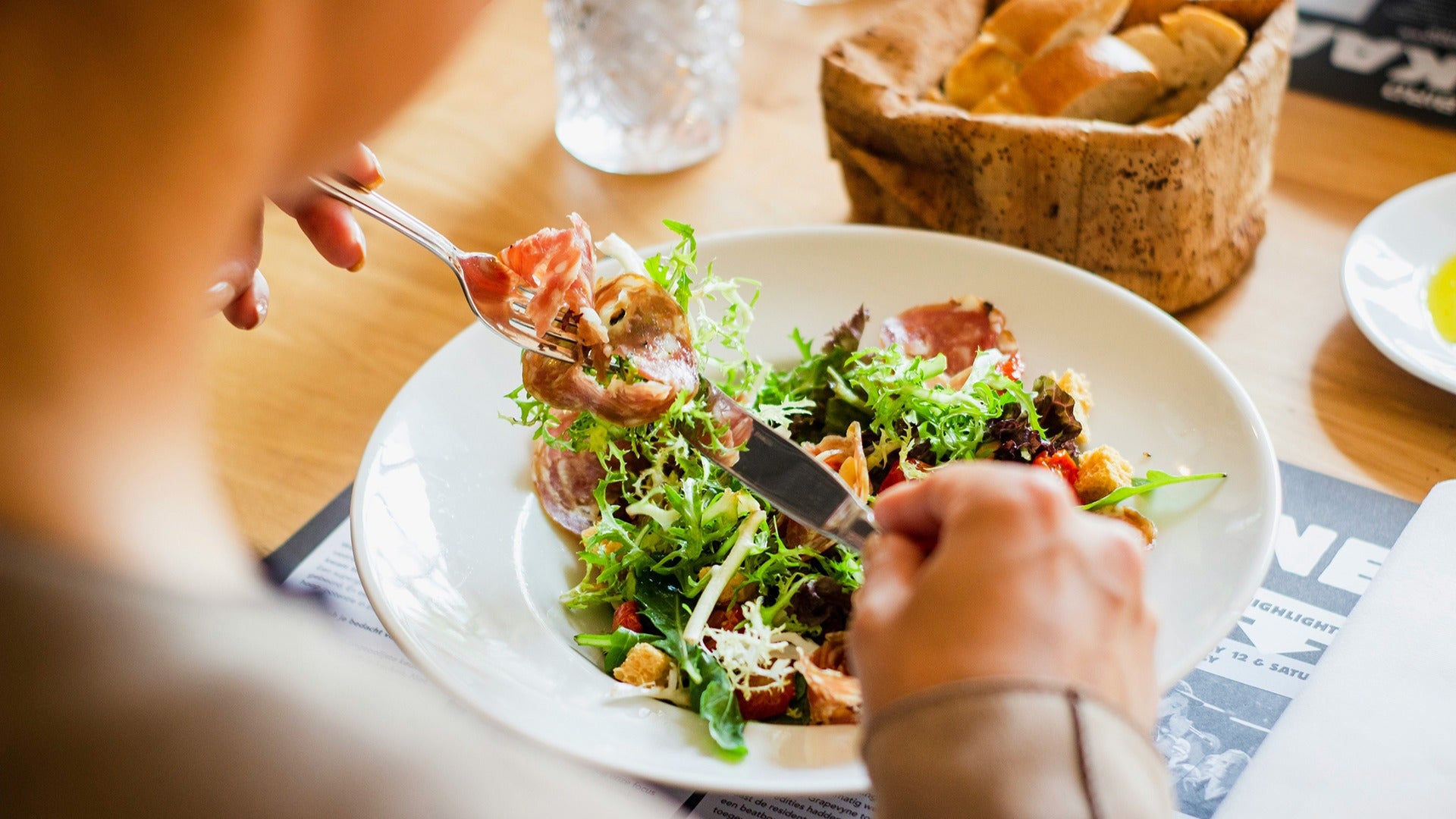 a man eating a salad with bread on the side