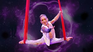 an acrobat midair balancing on cloth ropes