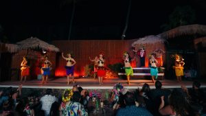 a group of hawaiian luau dancers performing on stage with an audience watching