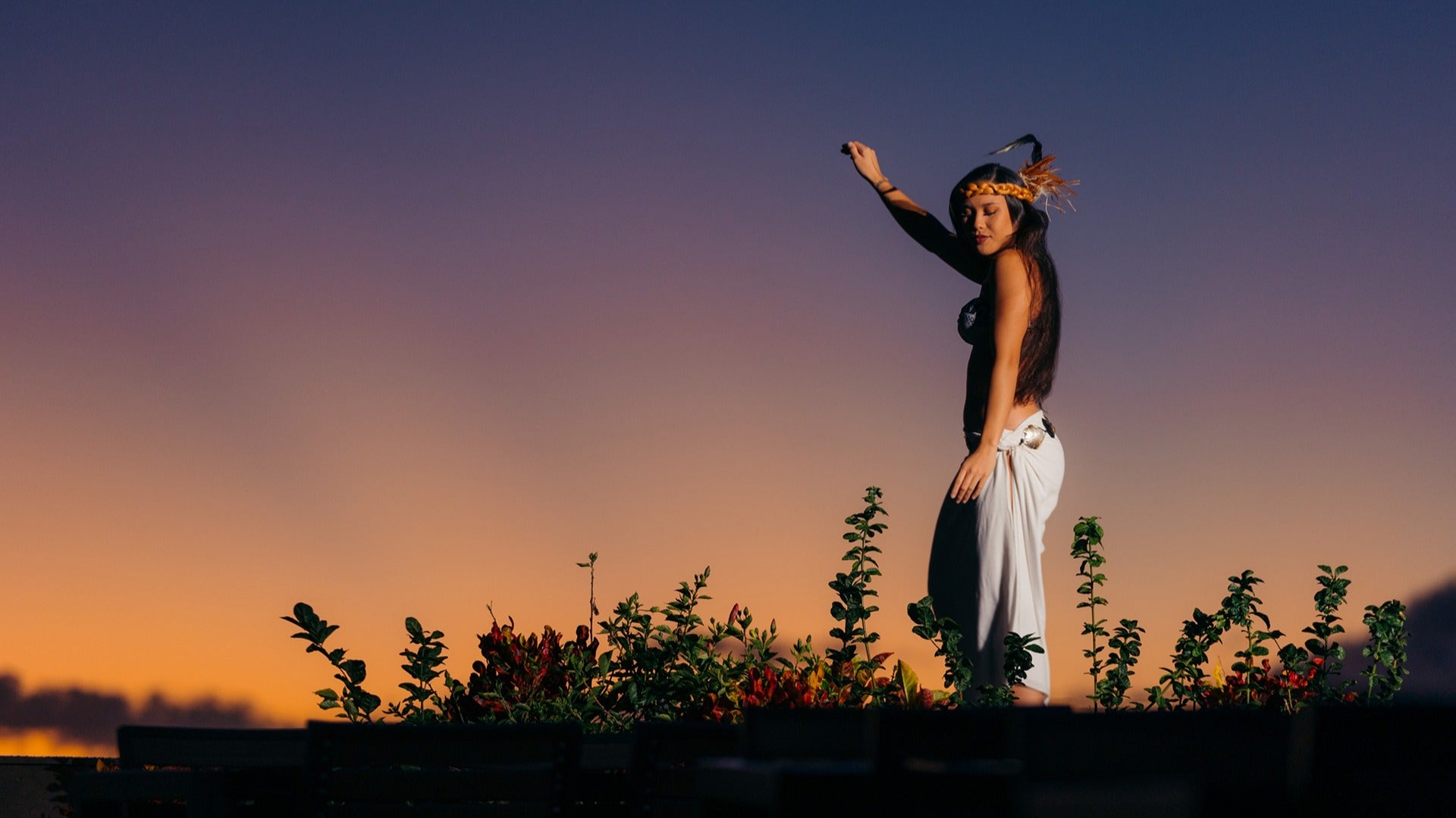 a hawaiian girl dancing with plants and flowers at her feet
