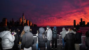 group of tourists on a cruise looking at the sunset with the new york skyline