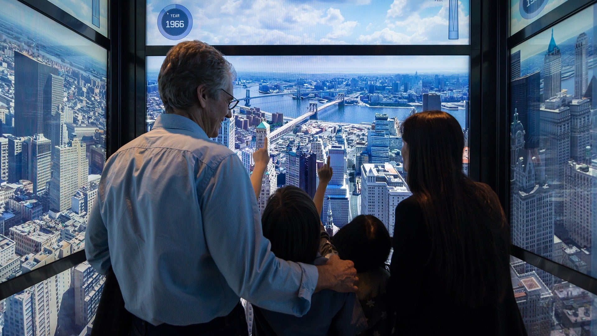 a family with kids in an elevator with a view of the new york skyline below