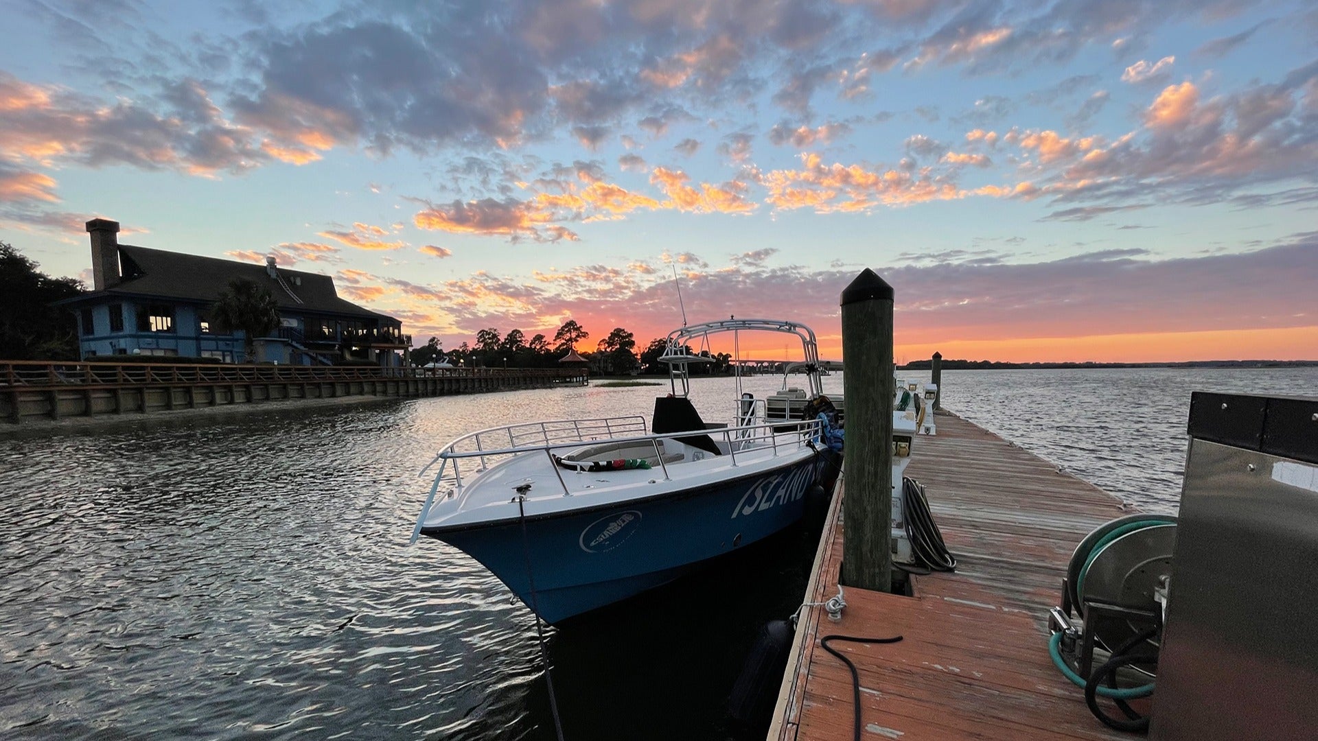 a boat docked on a harbour with a view of the ocean and sunset at the back