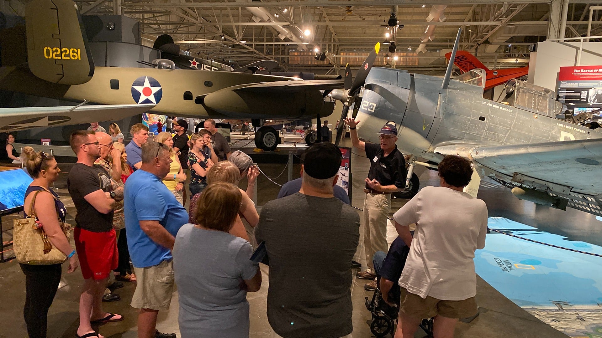 people listening to a tour guide in the pearl harbor aviation museum