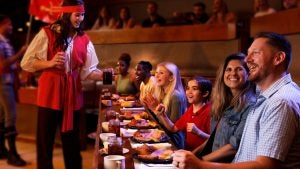 a family eating at a dinner show, being served juice by a waitress dressed as a pirate