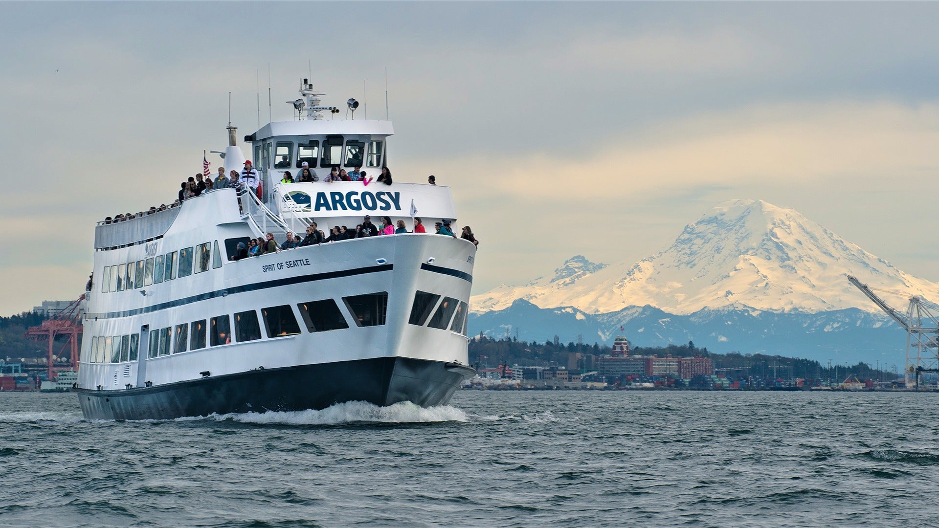 a cruise on the ocean with passengers and a view of snowy mountains at the back