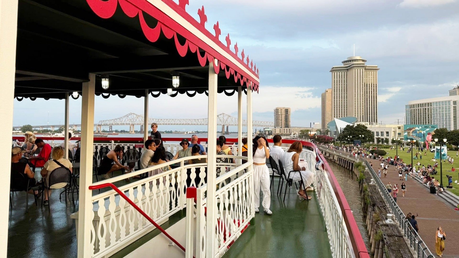 people aboard a steamboat cruise docked on the pier with a park on the side