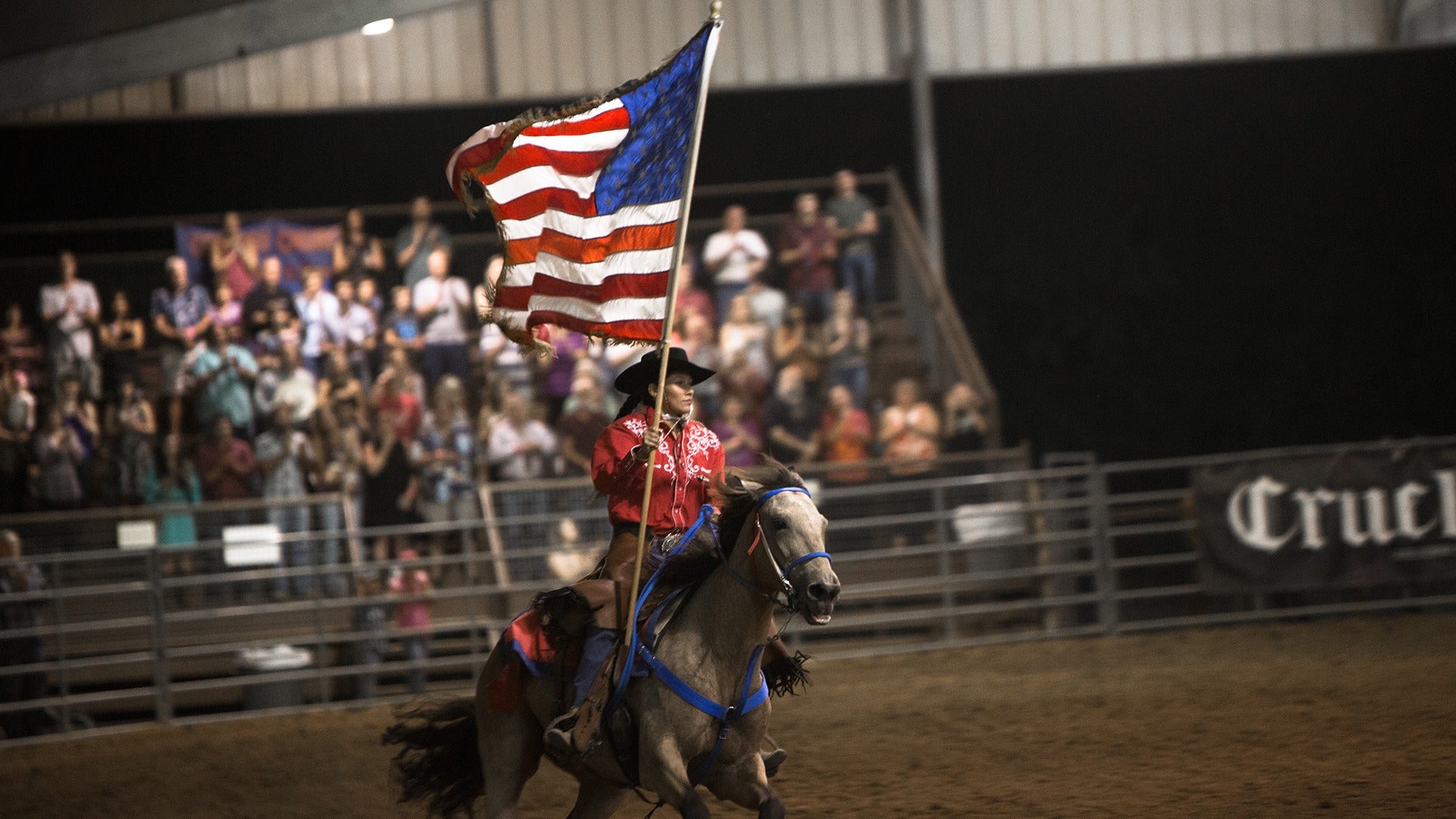 a cowboy holding the american flag in front of an audience