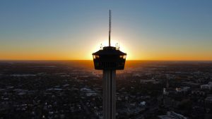 a tall tower set against the sunset with a view of the city below