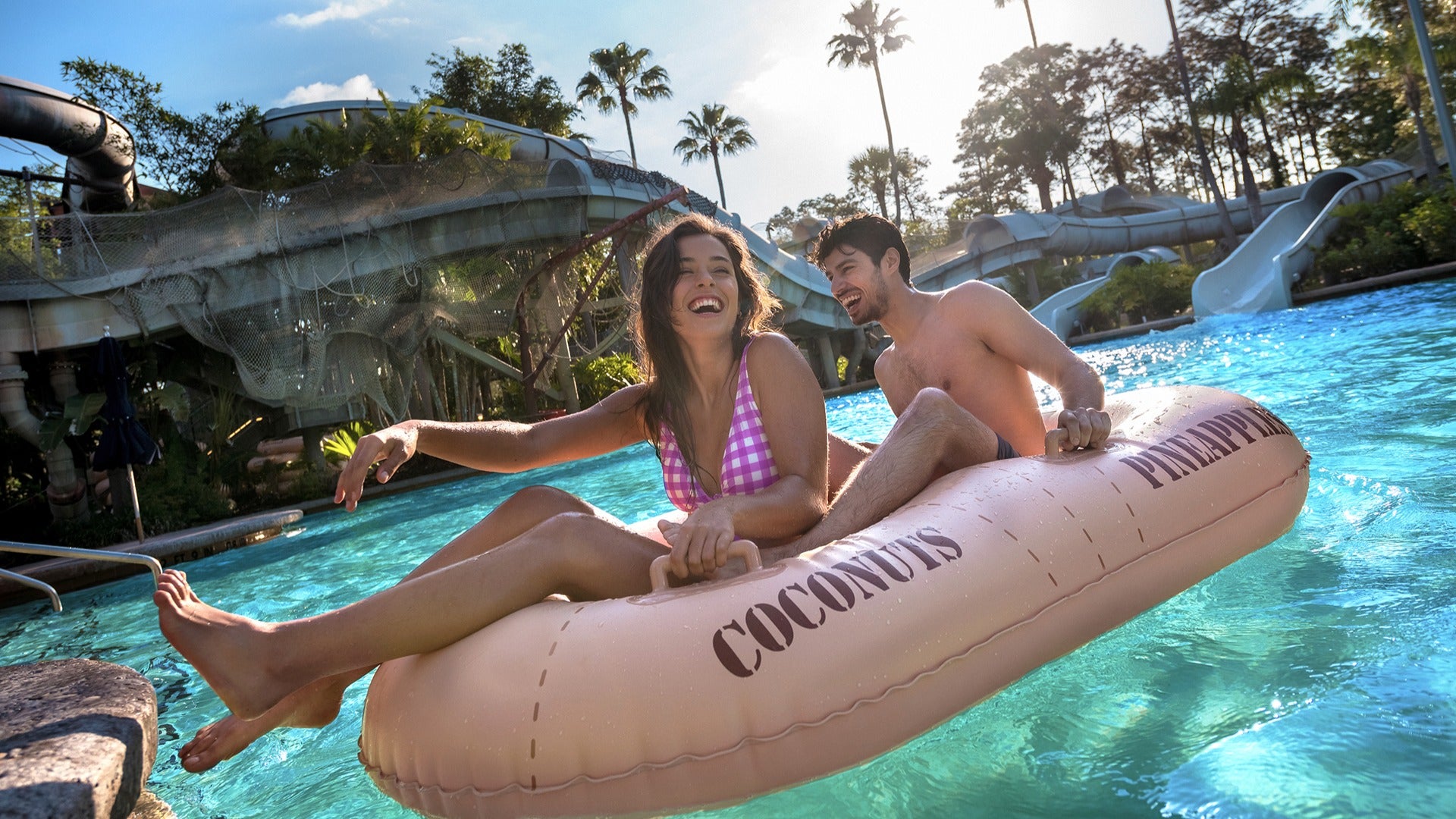 a couple riding a pool inflatable with water slides at the back