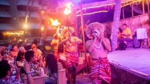a group of luau dancers performing in front of an audience holding a shell and torches
