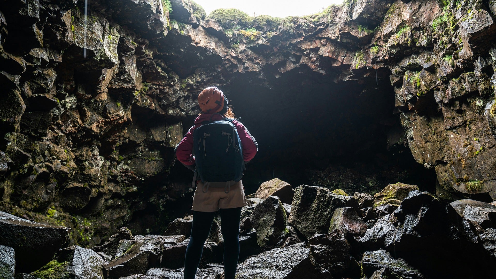 a woman in a cave looking up at the entrance