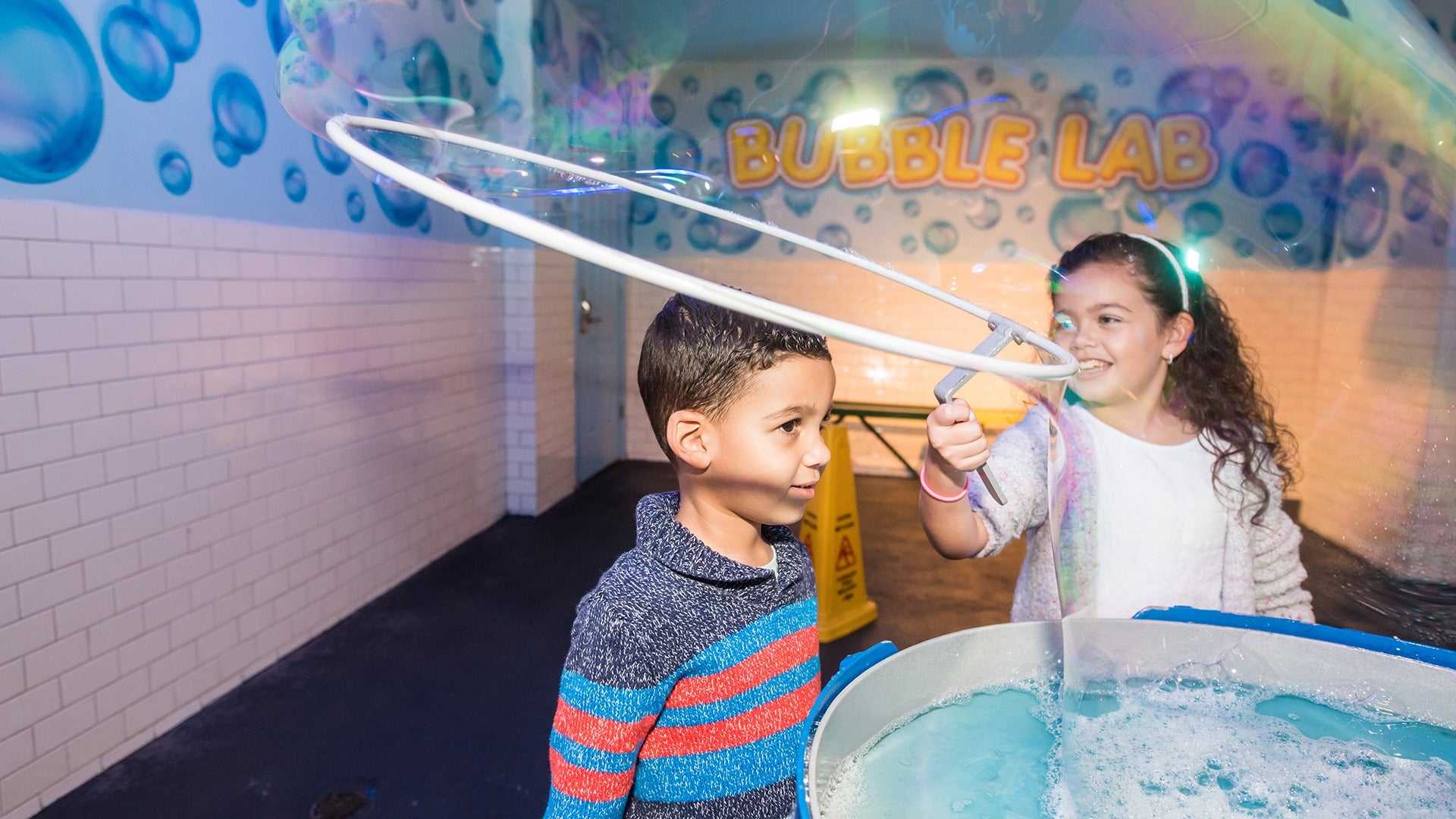 kids playing in a bubble lab with big bubbles and tiled walls