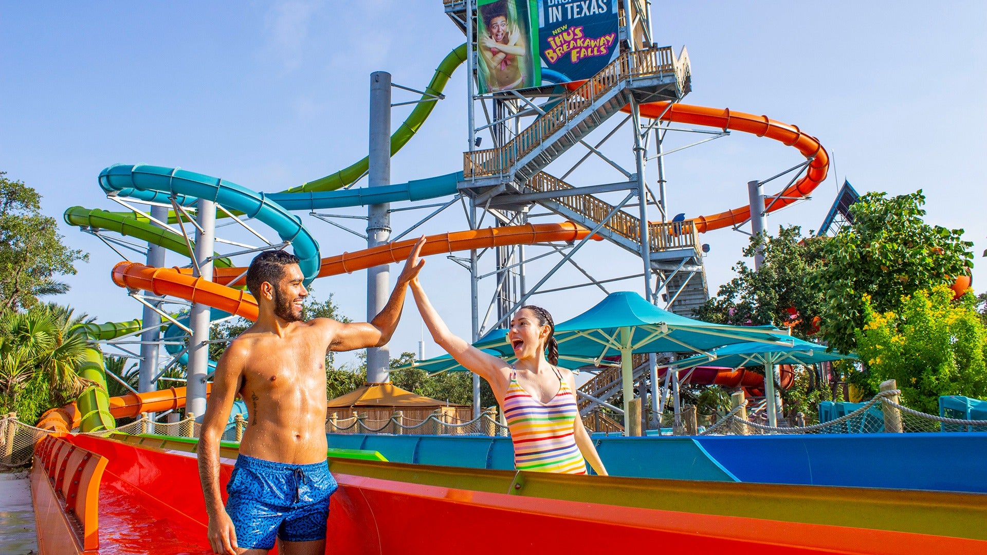 a couple doing a high five at the bottom of a water slide