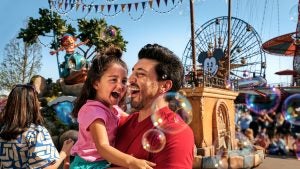 a father holding his daughter while a parade is ongoing at the back