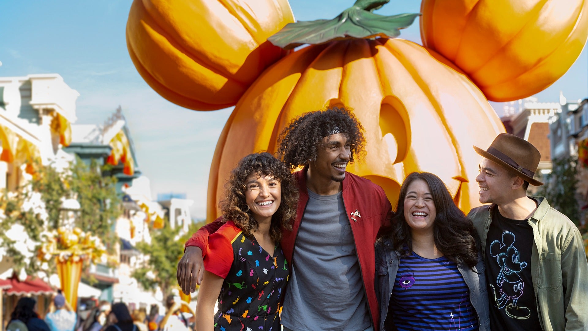 a group of friends posing in front of a mickey-shaped pumpkin