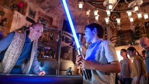 a kid holding a lightsaber at a disneyland attraction