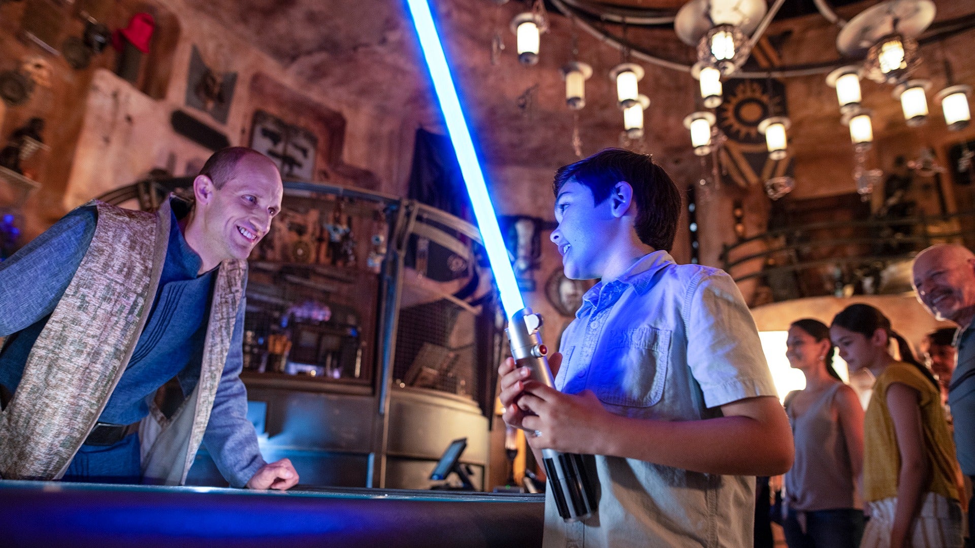 a kid holding a lightsaber at a disneyland attraction