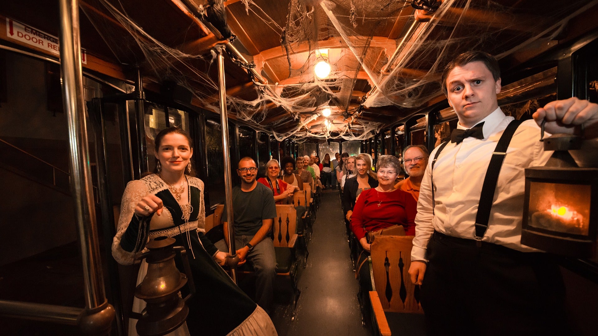 a group of people in a haunted trolley with two guides in front dressed in costumes