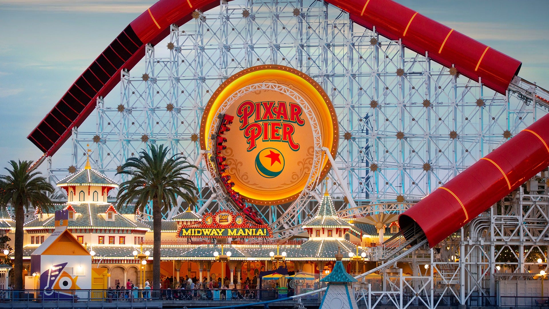 a roller coaster with bright lights and people lined up for it
