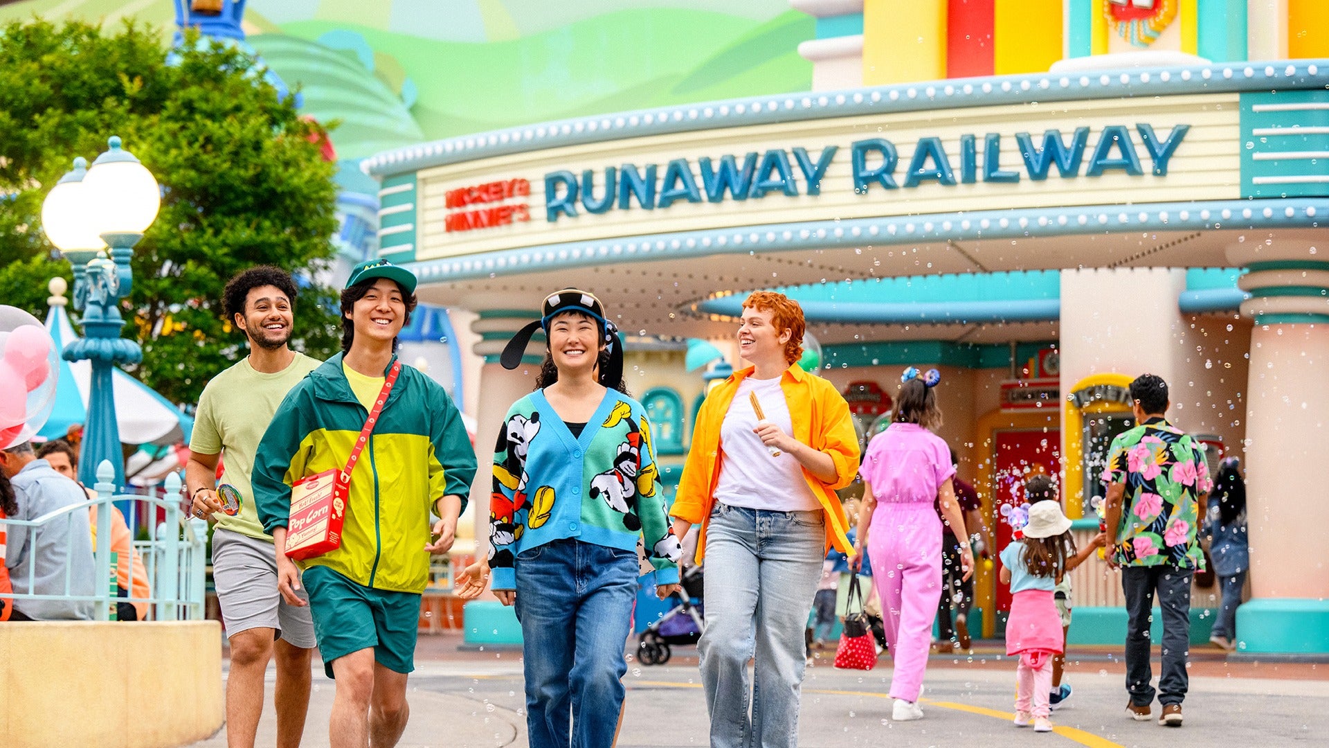 a group of friends eating churros and walking at a theme park with rides and attractions behind them