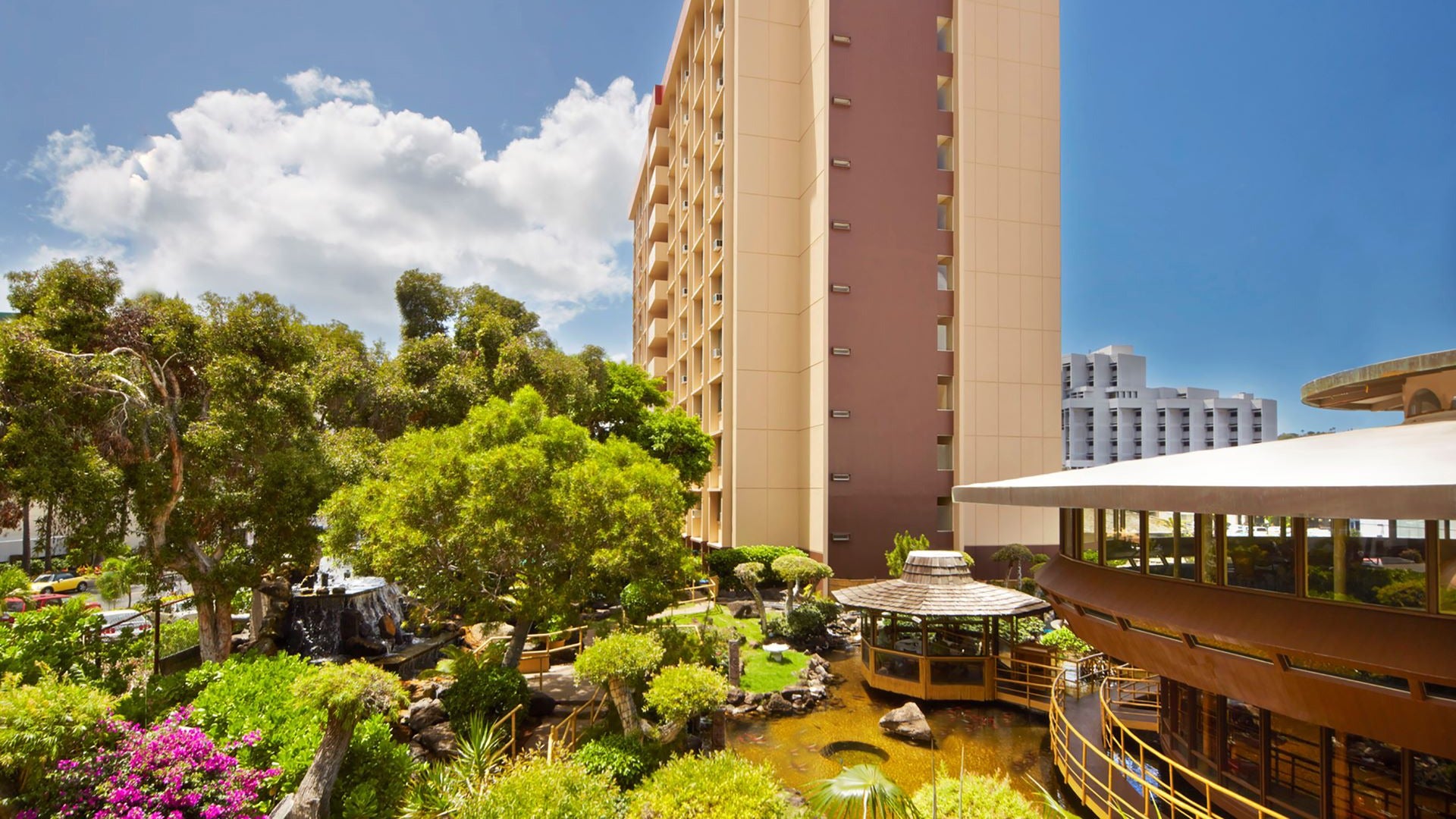 a hotel exterior with a pagoda and koi pond in front