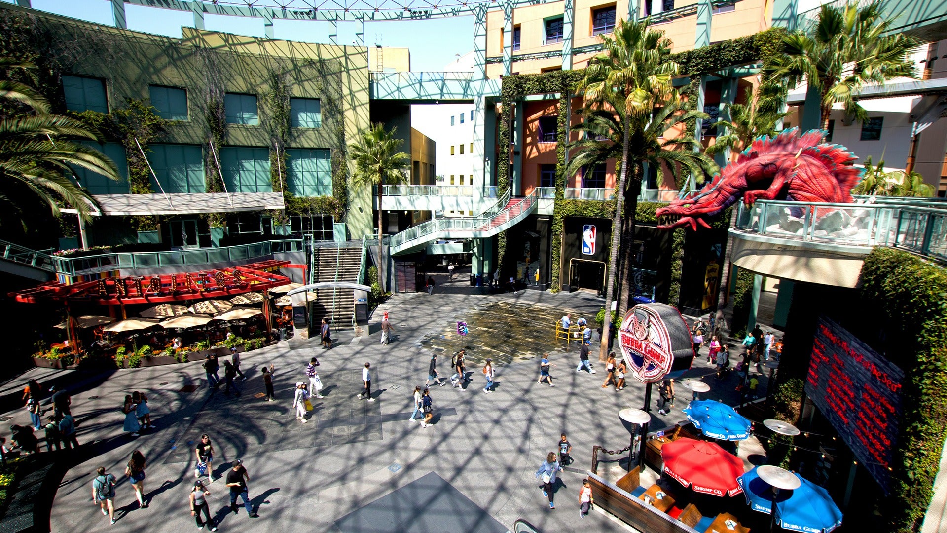 an indoor mall with various plants, trees, restaurants and a dragon feature