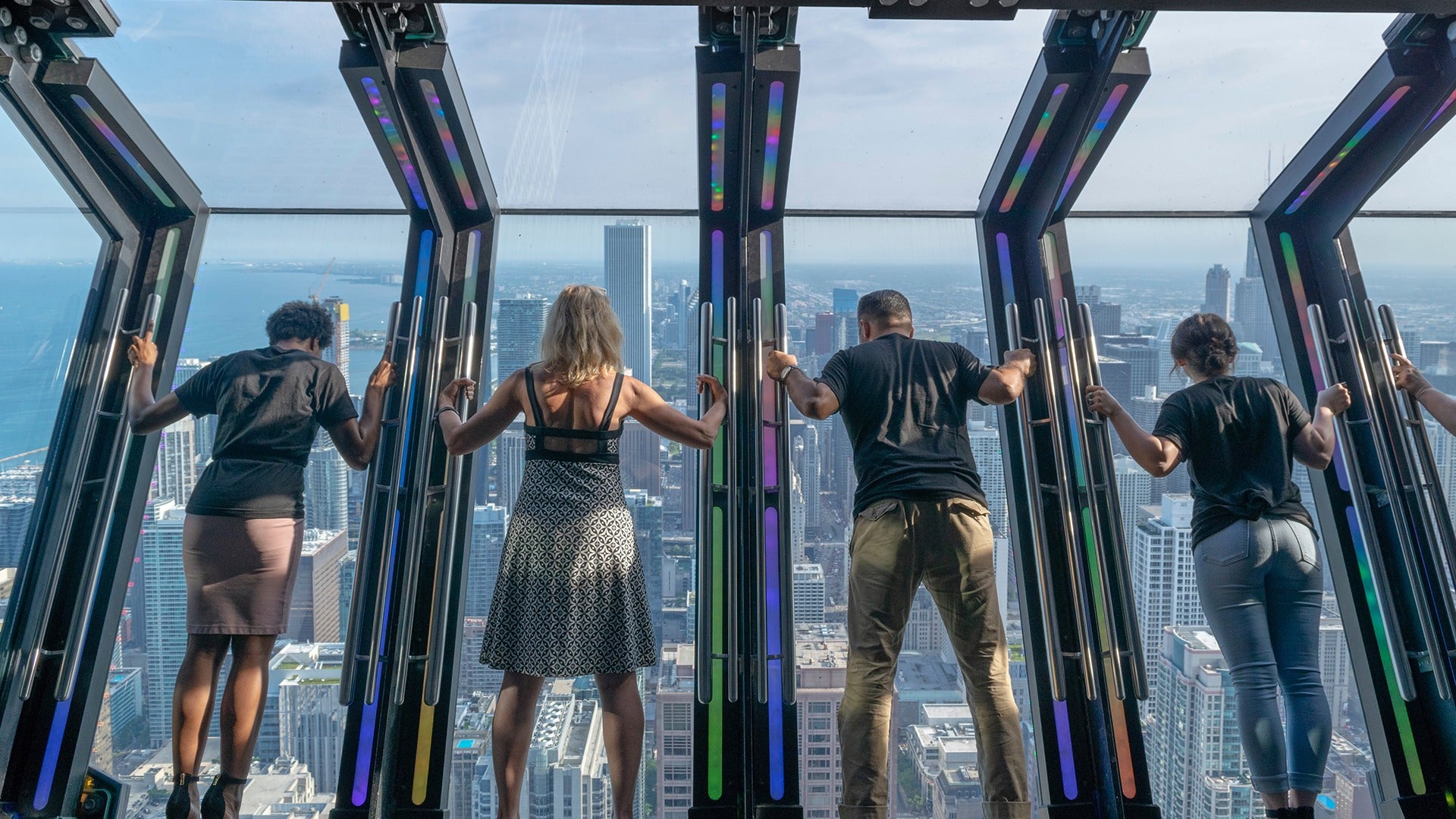 people on a city viewing ledge with chicago skyline below