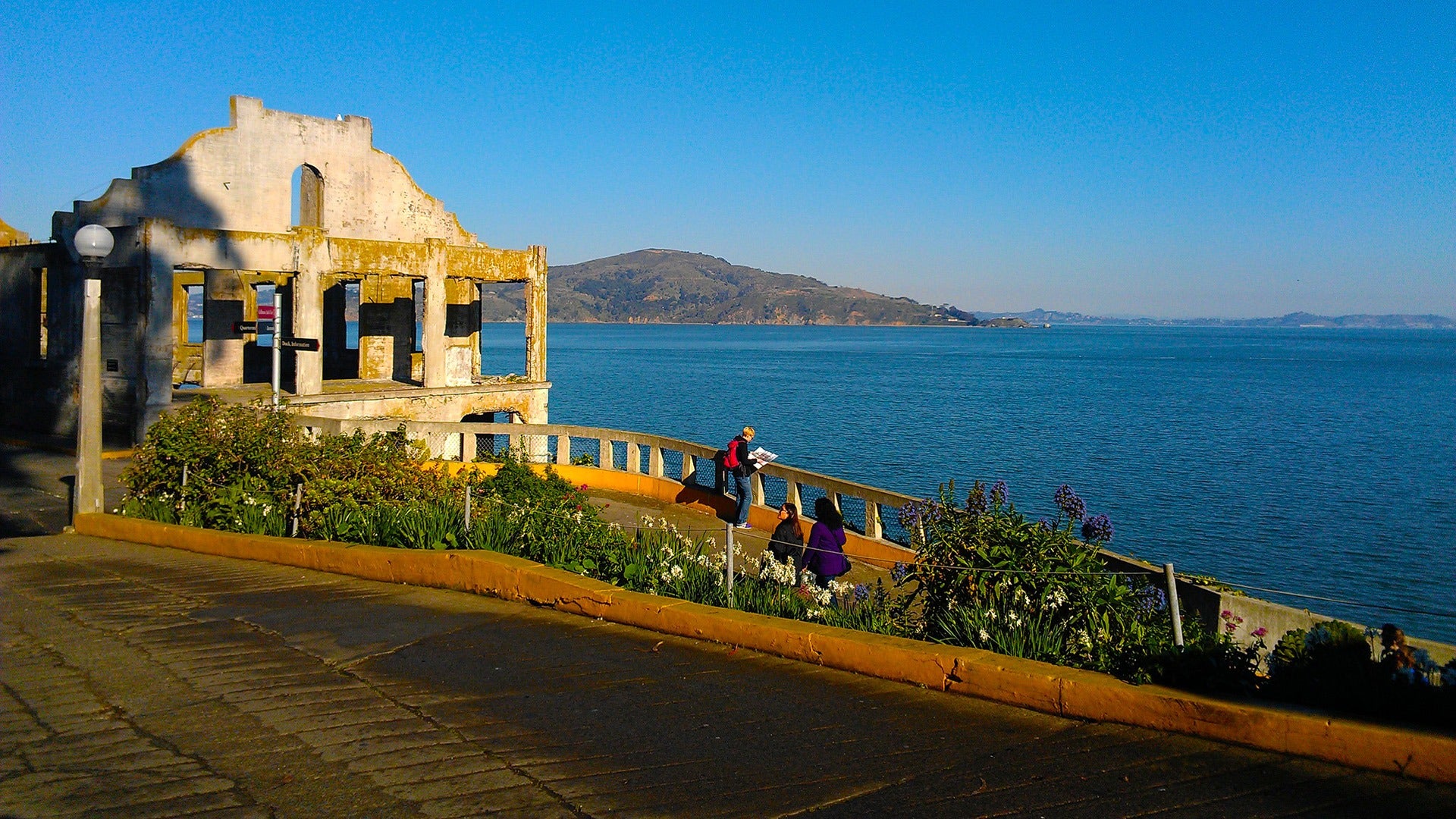 people exploring an old structure with a view of the ocean behind