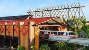 a train moving from the station, surrounded by trees and wooden roof spikes